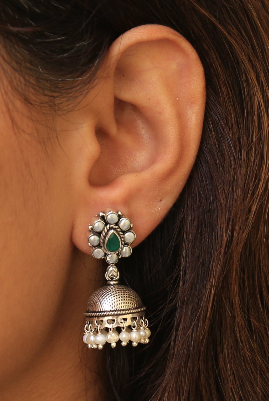 Close-up of the Akansha Pearl Silver Jhumkas featuring emerald and pearl kundan work, pearl droplets, and textured silver surface. These earrings exude elegance and sophistication, adding a touch of glamour to any ensemble.