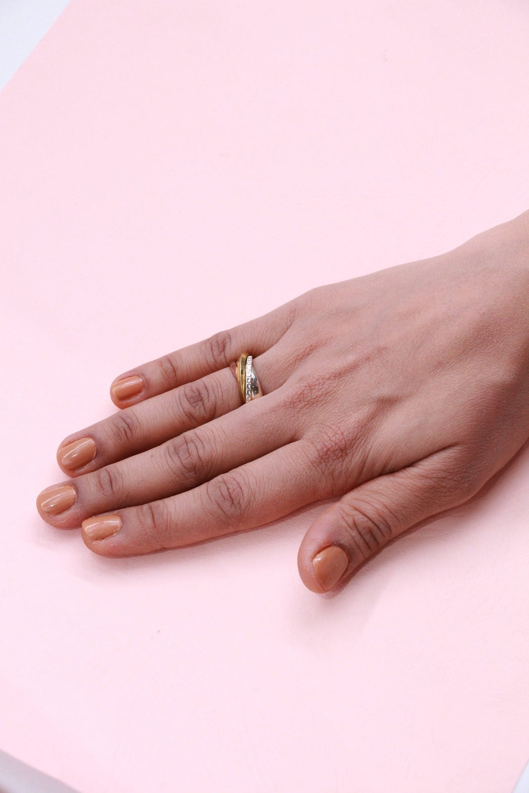 A close-up of a 3-tone silver band cluster ring featuring a mix of silver, white gold, and rose gold with sparkling stones. The ring exudes elegance and modernity.