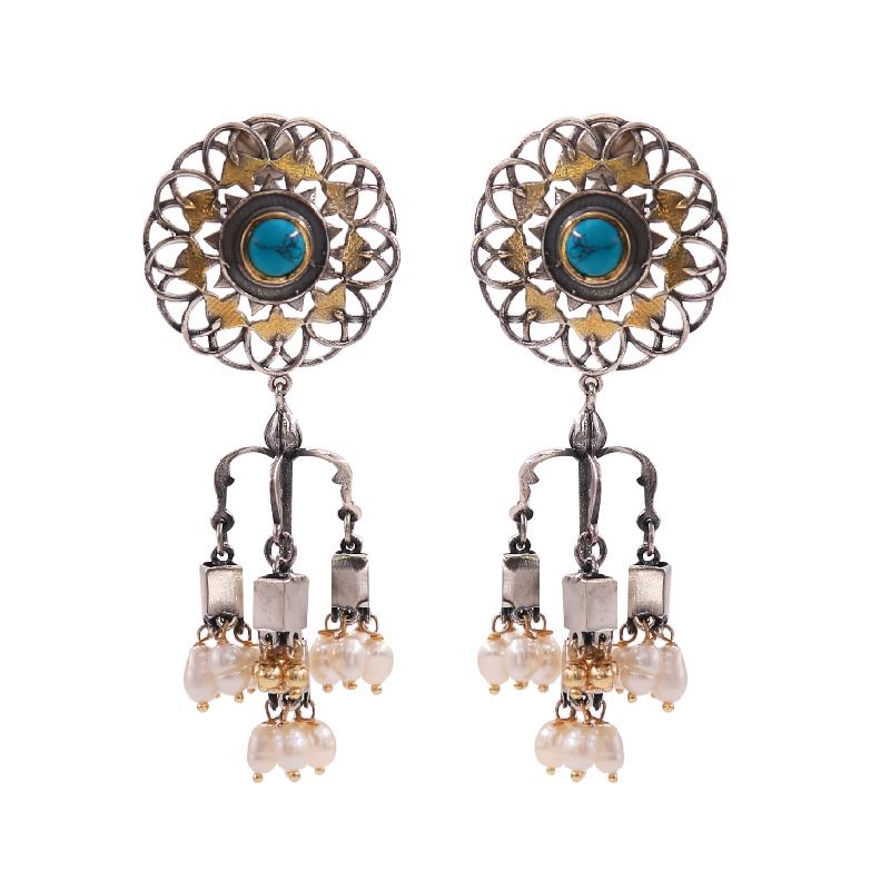 Close-up of the Mandala Dual Tone Chandeliers showcasing a dual-tone mandala design with turquoise kundan stones and rice pearl droplets. These earrings exude elegance and charm, adding a pop of vibrant color and sophistication to any ensemble.